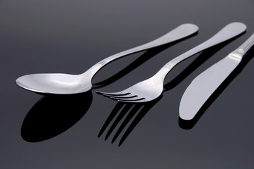 modern silver spoon, knife, fork on the mirror background