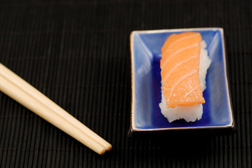 Chopsticks and sushi nigiri on black mat