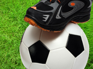 football shoe and soccer ball over green grass field