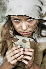 Poor beggar child with a piece of bread in her hands