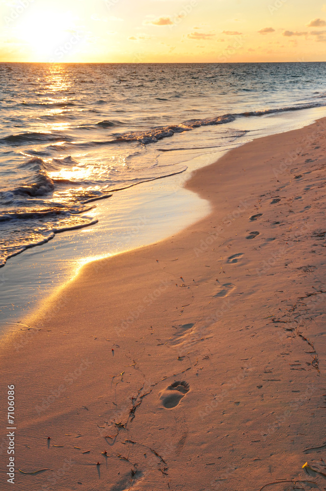 Poster Footprints on sandy beach at sunrise