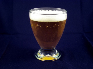 glass of beer with foam isolated on blue background