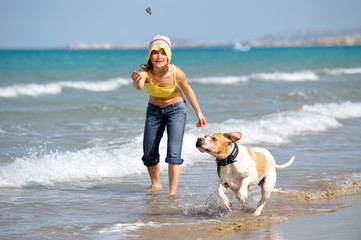girl playing with her dog on the beach on a summer day