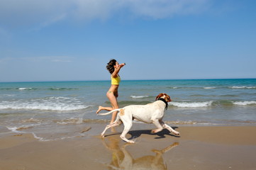 young woman playing with her dog on the beach