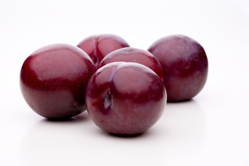 Fünf violette ganze Pflaumen auf weißem Hintergrund