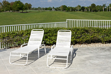 Pool chairs on patio with golf course in background