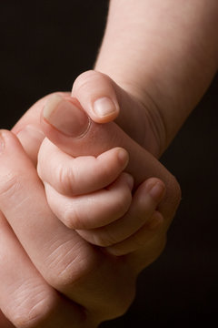 Baby's hand gripping adult finger