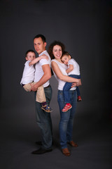 parents hold children on hands on dark background