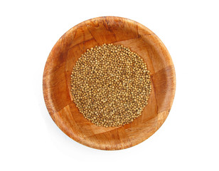 Coriander dried seeds spice in wooden dish isolated