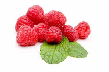 Rote Himbeeren liegen auf zwei grünen Minze Blätter