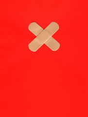 Two plasters forming a cross on red background