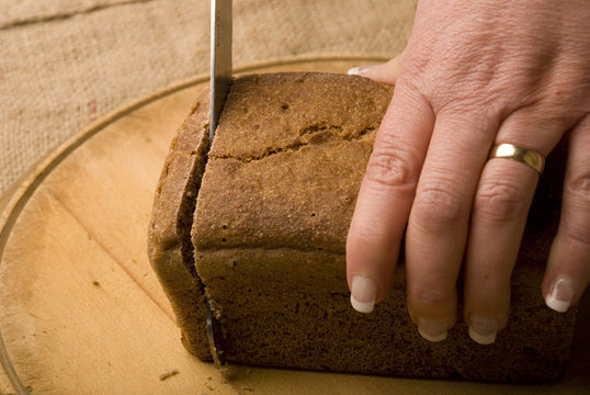 Woman Slicing Loaf Of Rye Bread