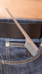 Grey hairbrush with the thin end in a pocket of jeans.
