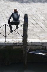Gondoliere wartet auf einem Geländer sitzend auf Touristen in Ve