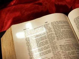 Naklejka premium Cross of light over John 3:16 in open Bible