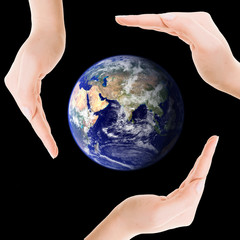 Earth surrounded by three hands.
