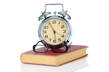 book with alarm clock and eyeglasses
