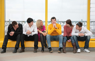 group of young people sit on footbridge