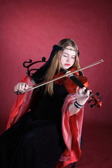 beautiful girl in an ancient dress plays on a violin