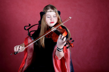 beautiful girl in an ancient dress plays on a violin