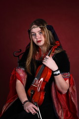 beautiful girl in an ancient dress plays on a violin