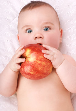 surprised baby boy eating red apple  over white background