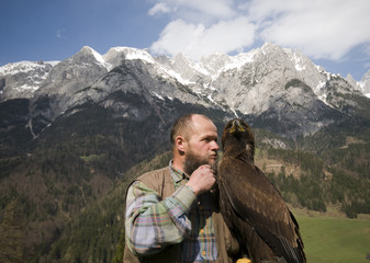 Falkner flüstert mit einem Steinadler vor einem beschneiten Gebi