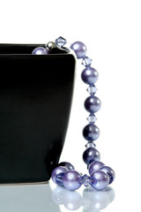 Purple necklace hanging from black glass bowl
