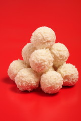 Pile is chocolate balls covered with coconut flakes on red