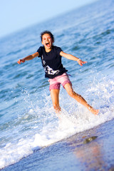  young girl having fun being splashed by the rolling waves 