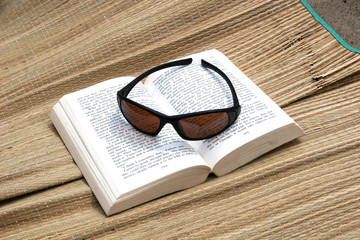 sunglasses and book on beachmat