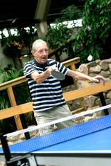 Active senior gentleman playing indoor table tennis.