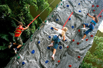 Young children doing rock climbing in an indoor sports center.