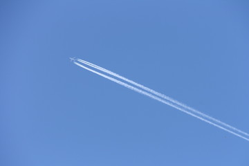 Plane in blue sky with trail
