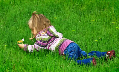 little girl walks in the spring on a young grass