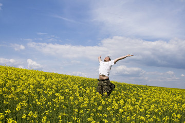 Young attractive man jumping in summer field