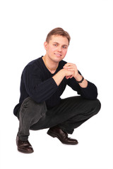 Young man sits on one's hunkers