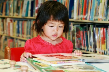 little girl read book in library