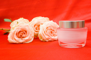 roses and cosmetic cream on a red background