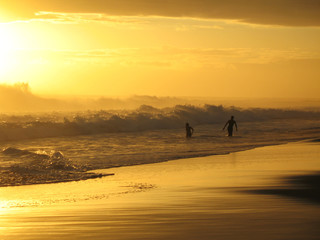 Fototapeta na wymiar couple amoureux jouant dans les vagues au coucher du soleil
