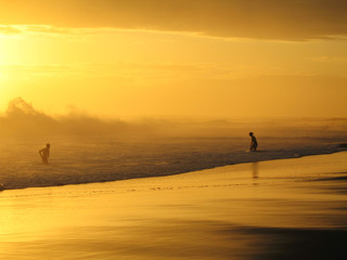Fototapeta na wymiar couple jouant dans les vagues au coucher du soleil
