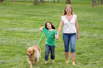 Obraz premium Mother and Daughter Walking the Dog in the Park