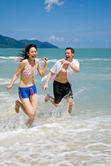 couple racing on the beach with joy