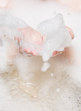 Woman in a bath blowing foam