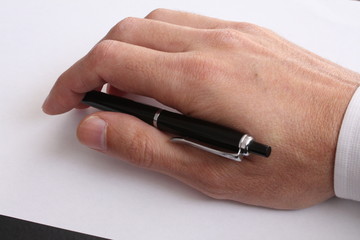 Hand with pen resting on blank piece of paper