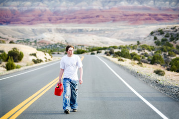 Obraz premium teenager out of gas walking down road with empty can
