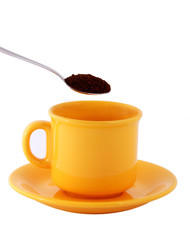 Yellow cup with spoon of milled coffee