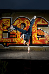 Girl break dancer posing on a grunge graffiti wall