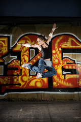 Girl break dancer jumping on a grunge graffiti wall