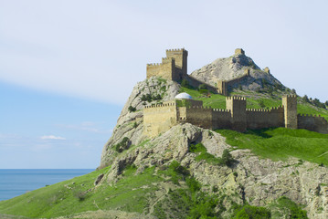 Fototapeta na wymiar Genoese fortress on green mountain over sea in Crimea